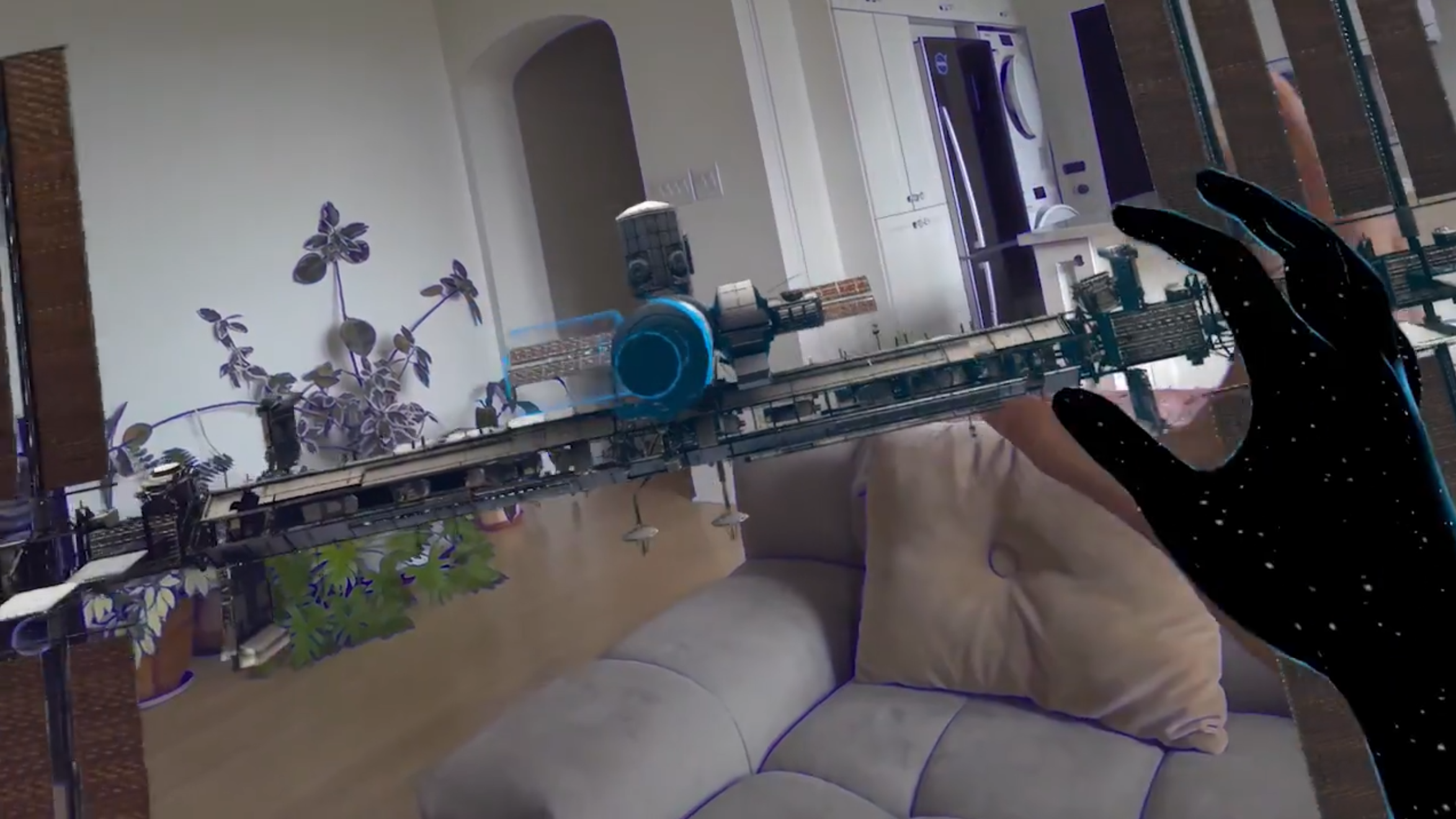 First person view of a miniature model of the ISS floating in a living room with a cosmic arm reaching towards it.